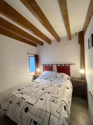 une chambre avec un grand lit dans une pièce avec des plafonds en bois dans l'établissement 6VOLT21 Appartement pour 6 personnes au cœur du Faubourg, à Collioure