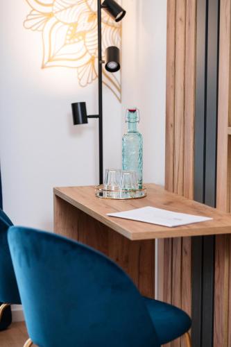 a table with a blue chair and a bottle on it at Pension Auszeit Velden in Velden am Wörthersee