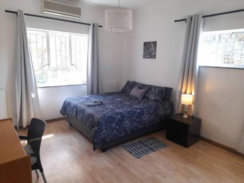 a bedroom with a bed and a table and windows at Kuiseb High Five in Windhoek
