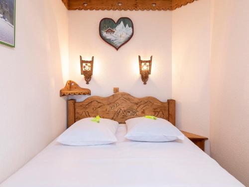 - un lit avec 2 oreillers blancs et un cœur sur le mur dans l'établissement Charmant appartement 2P avec balcon, WiFi et casier à skis à Avoriaz - FR-1-314-128, à Avoriaz