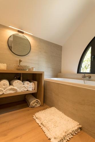 a bathroom with a tub and a sink and a mirror at La Cabane d'Amae in Marche-en-Famenne