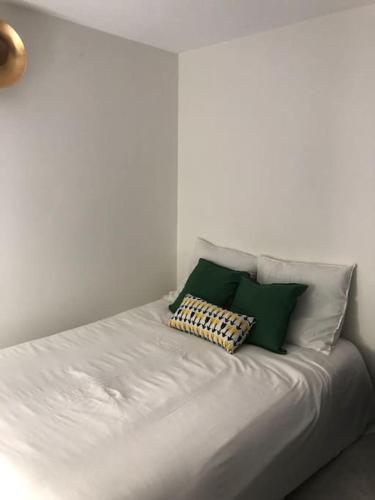 - un lit blanc avec des oreillers verts et blancs dans l'établissement Séjour en pleine nature, à Romeyer
