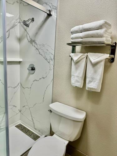 a bathroom with a toilet and a shower with towels at Days Inn by Wyndham Williams in Williams