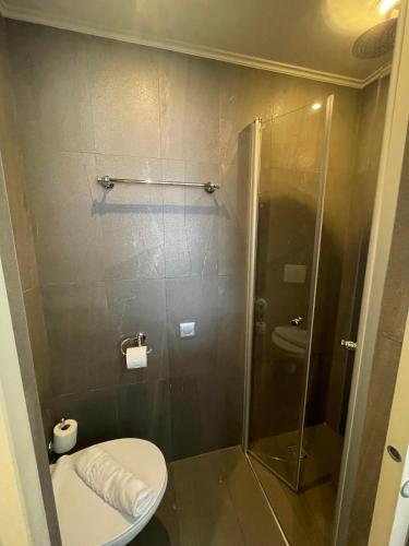 a bathroom with a toilet and a glass shower at Hôtel Villa-Lamartine in Arcachon