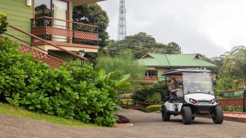 a woman driving a golf cart in front of a house at Ficus Sunset Suites in Monteverde Costa Rica