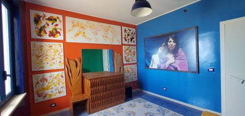 サント・ステーファノ・ディ・カマストラにあるAtelier sul Mare Suite d'Autoreの壁に女性の絵が飾られた青い部屋