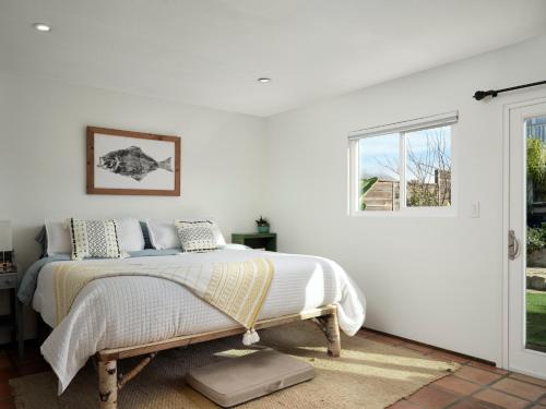 Un dormitorio blanco con una cama y una ventana. en Baywood Casita- kids, dogs, hot tub, en Baywood Park