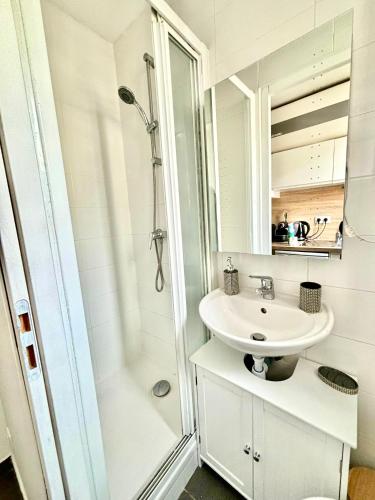 une salle de bain blanche avec un lavabo et une douche dans l'établissement À Deux pas du Metro Louise Michel, à Levallois-Perret