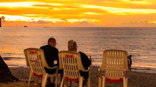 a couple sitting in chairs on the beach watching the sunset at Deng's Budget Room in Kamala Beach
