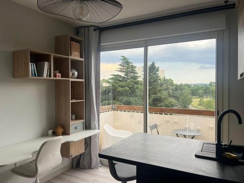 un bureau avec un bureau et une fenêtre avec vue dans l'établissement Le Studio - Parking & Balcon, à Toulouse