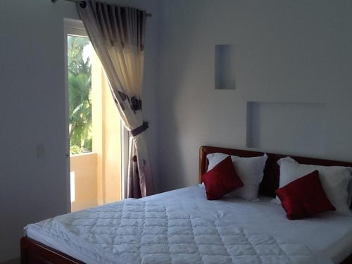 una camera da letto con un letto con cuscini rossi e una finestra di Areca Resort a Mui Ne