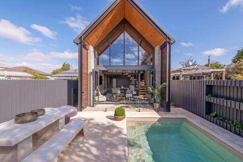 a home with a swimming pool and a house at Divine on Derby - Christchurch Holiday Home in Christchurch