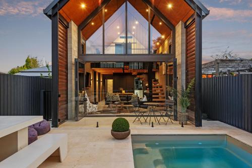 a home with a swimming pool and a glass house at Divine on Derby - Christchurch Holiday Home in Christchurch