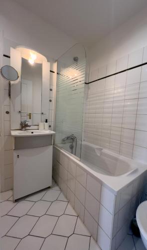 une salle de bain blanche avec une baignoire et un lavabo dans l'établissement Appartement à 5 mins Tour Effeil, à Paris