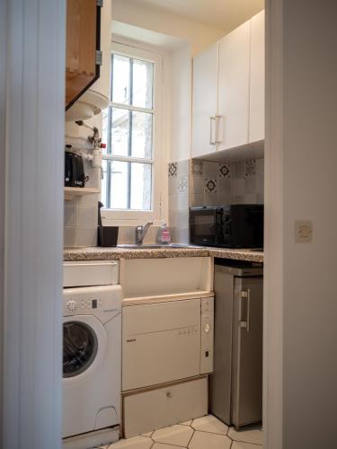 une cuisine avec une machine à laver et une fenêtre dans l'établissement Appartement à 5 mins Tour Effeil, à Paris