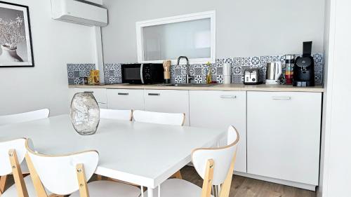 une cuisine blanche avec une table et des chaises blanches dans l'établissement Suite Dalmate - Check in h24 - Wifi, à Lyon