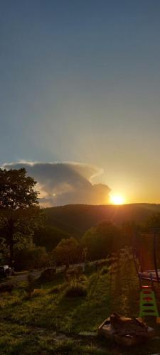 a sunset on a field with a chair in the foreground at Odaia Bunicilor in Feldru