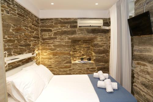a bedroom with a white bed and a stone wall at Chora's Stonehouse in Andros