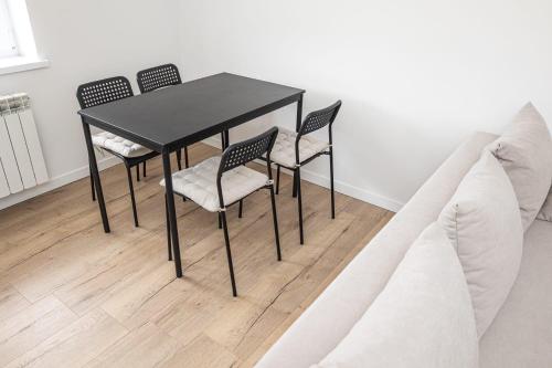 a black table with four chairs and a couch at Apartament z ogrodem - 2-Pokojowy in Radom