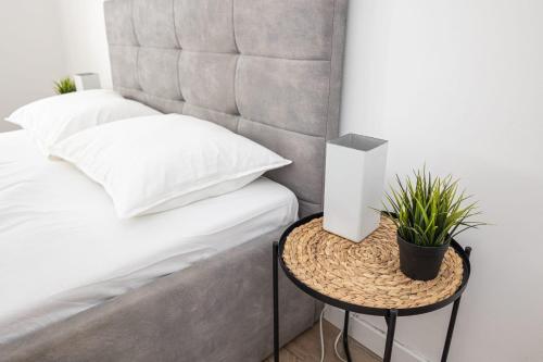 a bed with a side table with a plant on it at Apartament z ogrodem - 2-Pokojowy in Radom