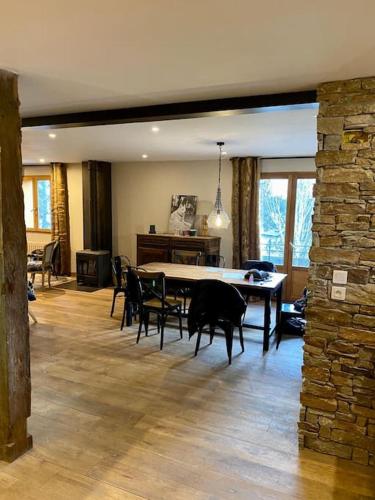 - un salon avec une table, des chaises et un mur en pierre dans l'établissement Chalet l'Atypique - 10 personnes, à Bolquère-Pyrénées 2000