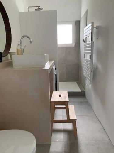 une petite salle de bain avec un lavabo et un tabouret dans l'établissement Maison de Campagne proche plage, à Blainville-sur-Mer