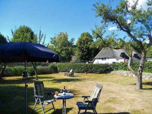 a table and chairs under an umbrella in a yard at Haus Arfsten "Deichgraf", Nieblum in Nieblum