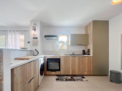 une cuisine avec des armoires en bois et un four à plaques de cuisson dans l'établissement Ile Rousse T2 proche centre-ville, à LʼÎle-Rousse