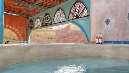 two bottles of beer sitting next to a swimming pool at Zimmerbus in ‘Ezuz