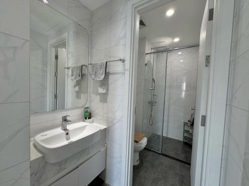 a white bathroom with a sink and a shower at Kim Chi House - Imperia Smart City - 1 BR 55m2 in Hanoi