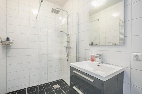 a white bathroom with a sink and a mirror at Modern appartement met gratis fietsen in Breda