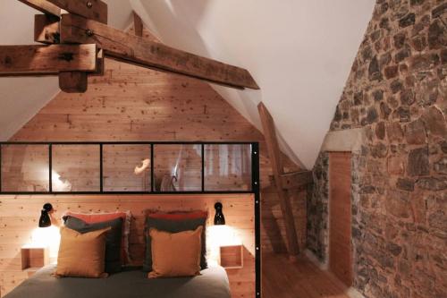 une chambre avec un lit avec un mur de briques dans l'établissement Jacuzzi privatisé en accès illimité Duplex, à Villedieu-les-Poêles