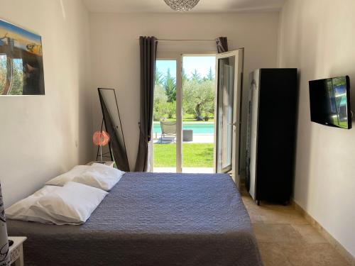 - une chambre avec un lit et une porte donnant sur une piscine dans l'établissement Mas du Soleil, à Caumont-sur-Durance