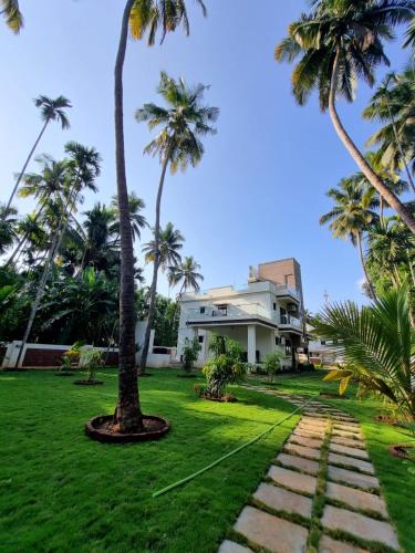 a house with palm trees in front of it at Whiteville Villa in Nandgaon