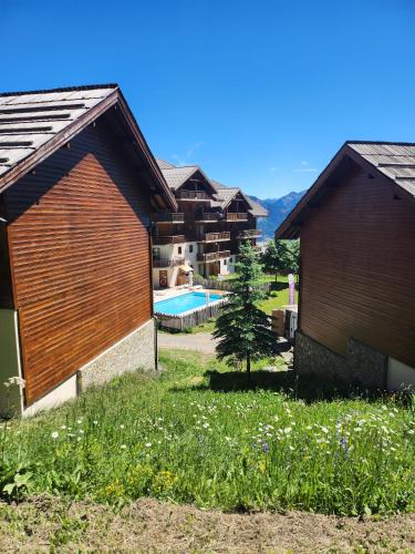 une cour arrière avec une piscine et deux bâtiments dans l'établissement Le Parc aux étoiles 1800, à Puy-Saint-Vincent