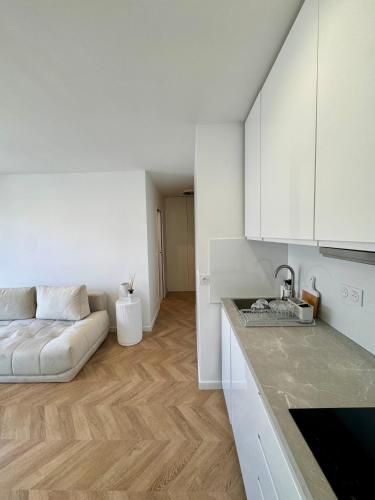 un salon avec un canapé et une cuisine dans l'établissement Charmant 2P Moderne et Épuré Près de la Mer et de la Célèbre Promenades des Anglais - Vivez le Rêve Méditerranéen, à Nice