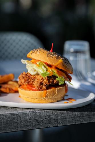 a chicken sandwich on a plate with fries at L'Esplanade Hôtel Restaurant Bar à vin in Le Pellerin