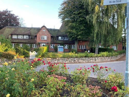 a street sign in front of a house with flowers at Heuboden, Nieblum in Nieblum