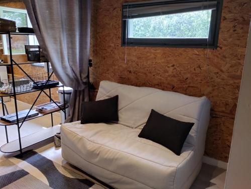 a white couch with two pillows sitting under a window at Studio Cosy Boxes Chevaux en sus in Agnez-lès-Duisans