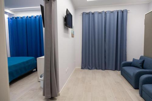 a living room with blue curtains and a tv at Pietre Azzurre Rooms in Pachino