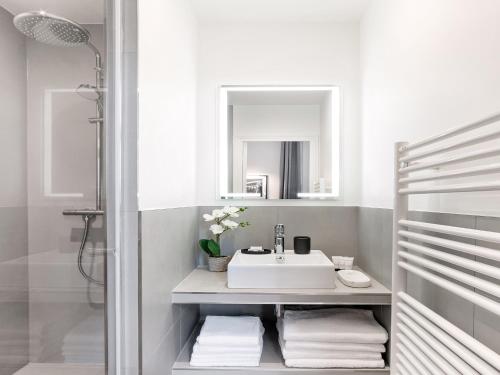une salle de bain blanche avec un lavabo et un miroir dans l'établissement LivinParis Luxury AC 3 Bedrooms Le Louvre II, à Paris