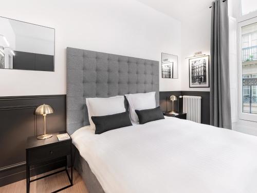 une chambre avec un grand lit blanc avec une grande tête de lit dans l'établissement LivinParis Luxury AC 3 Bedrooms Le Louvre II, à Paris