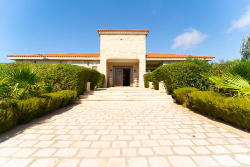 a brick pathway leading to a house with green hedges at La bastide in Al Matlīn