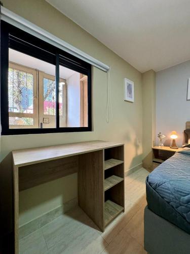 a bedroom with a desk and a large window at Hostelfc Usaquen in Bogotá