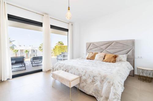 a white bedroom with a large bed and a balcony at Design Wohnung mit viel Luxus in Manilva