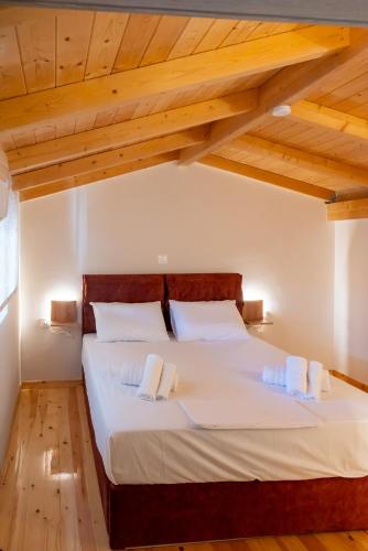 a bedroom with a large white bed with wooden ceilings at Paradise Apartments Artemida in Artemida