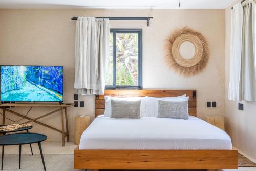a bedroom with a bed and a flat screen tv at Cucu Hotel El Cuyo in El Cuyo