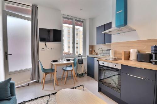 une cuisine avec des armoires bleues et une table et des chaises dans l'établissement The Cocoon - Studio-Apartment - Villeurbanne, à Villeurbanne