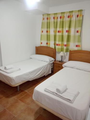 a room with two beds and a window at AlojamientoPILBAL in La Iruela