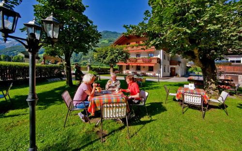 a group of people sitting at a table in the grass at Hotel Bad Winkel in Campo Tures